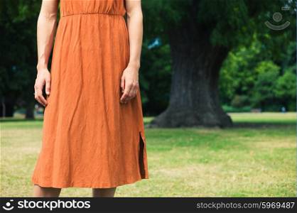 A young woman is standing by a big tree in a park
