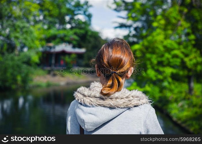 A young woman is standing by a lake in the park