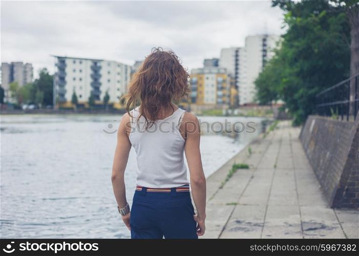 A young woman is standing by a marina in an urban area