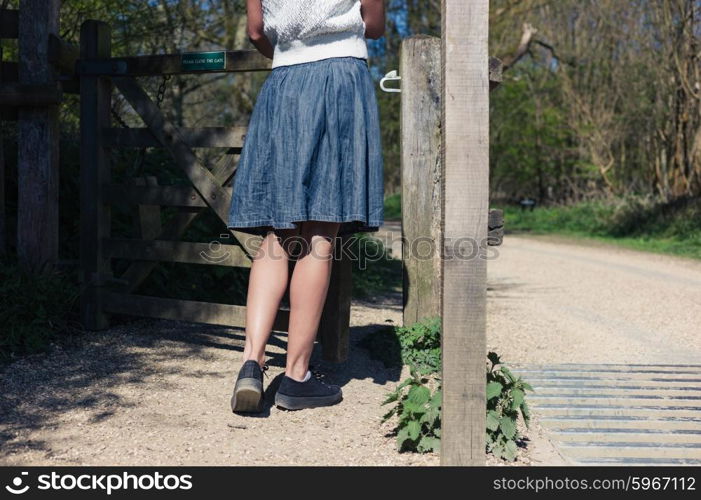 A young woman is standing by a wooden gate in a forest