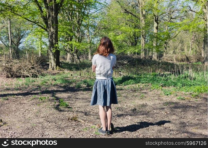 A young woman is standing in a forest