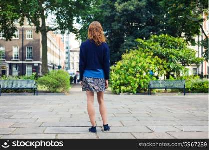 A young woman is standing in a park on a summer day
