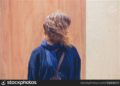 A young woman is standing in front of a wooden wall with two colors