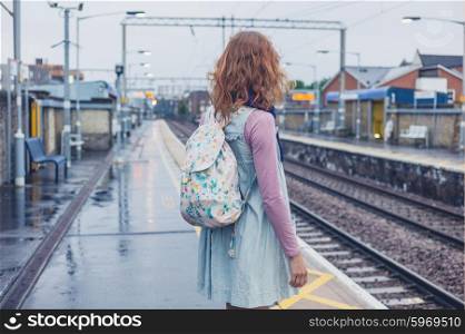 A young woman is standing on a platform and is waiting for the train