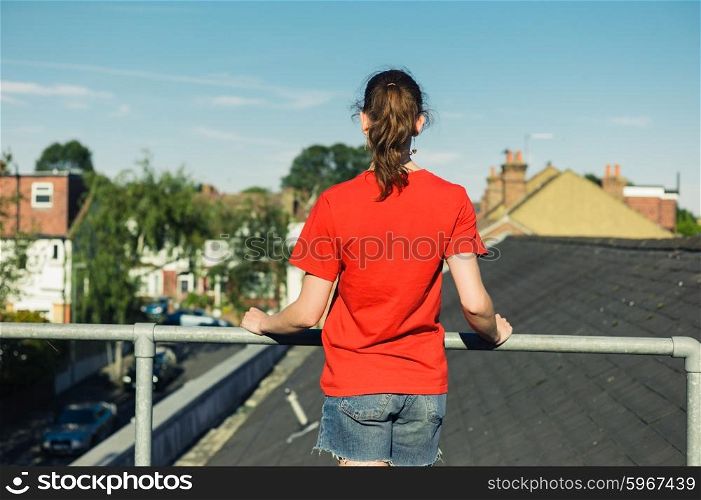 A young woman is standing on a roof on a sunny day