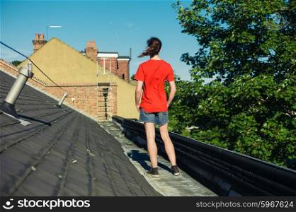 A young woman is standing on a roof on a sunny day