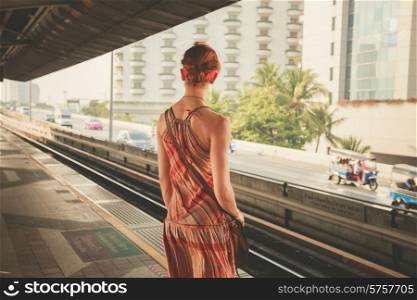 A young woman is standing on a train platform