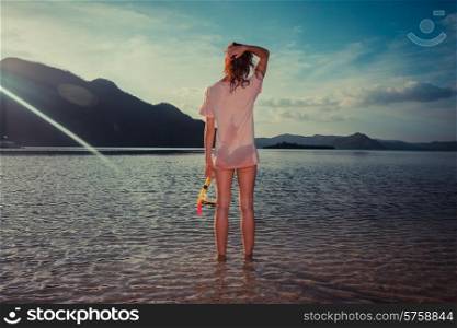 A young woman is standing on a tropical beach with snorkeling gear