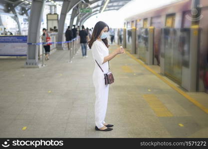 A young woman is standing on metro platform, wearing face mask , Covid-19 protection , New normal travel concept.. A young woman is standing on metro platform, wearing face mask , Covid-19 protection , New normal travel concept