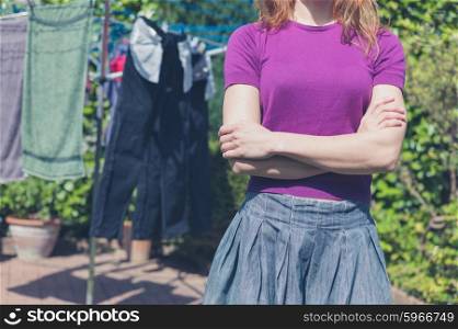A young woman is standing outside in her garden by her clothes line
