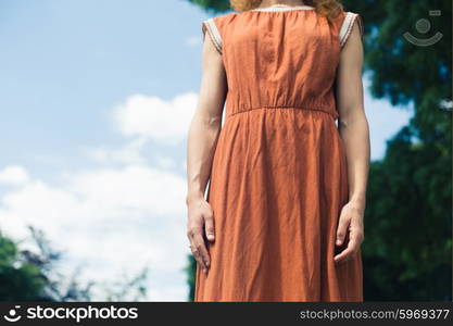 A young woman is standing outside in nature