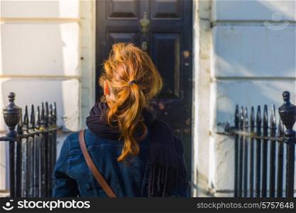 A young woman is standing outside the door of a Georgian terraced house