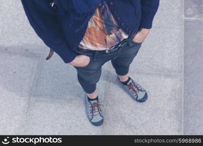 A young woman is standing outside with her hands in her pockets