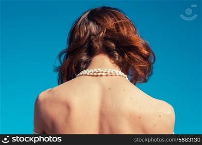 A young woman is tanning her back on a sunny day with a clear blue sky