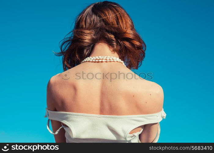 A young woman is tanning her back on a sunny day with a clear blue sky