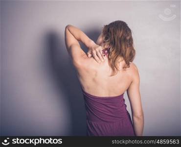 A young woman is touching her neck in pain