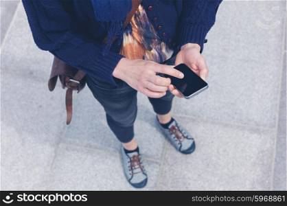 A young woman is using a smart phone outside in the city