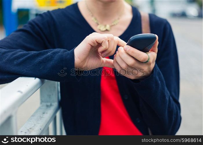 A young woman is using a smart phone outside in the street