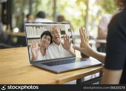 A young woman is using computer laptop to Video calling or Webcam to grandparent ,  telecommunications technology , parenthood family concept 