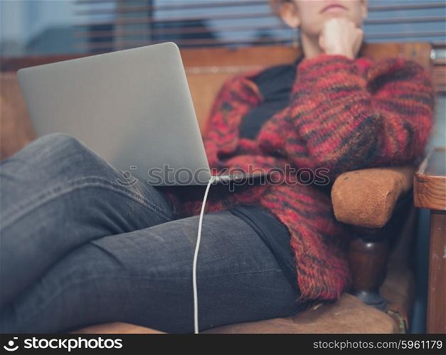 A young woman is using her laptop at home in her living room