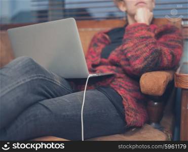 A young woman is using her laptop at home in her living room
