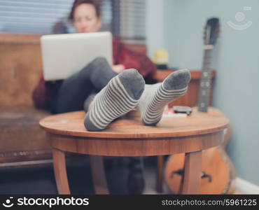 A young woman is using her laptop at home in her living room