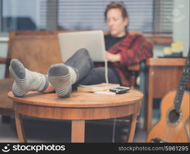 A young woman is using her laptop at home in her living room