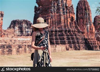 A young woman is using her smart phone amongst the ruins of an ancient temple
