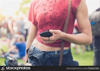 A young woman is using her smartphone at a music festival