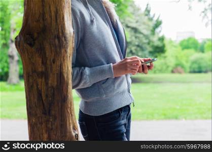 A young woman is using her smartphone in the park