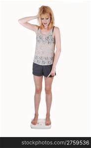 A young woman is very sad, standing on a scale and find out she gainssome wait, in shorts and a lace top on white background.