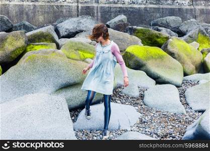 A young woman is walking amongst some vibrant rocks on the coast
