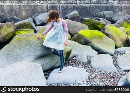 A young woman is walking amongst some vibrant rocks on the coast