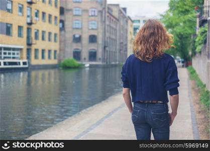 A young woman is walking by a canal in the city