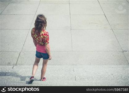 A young woman is walking down some steps outside in the summer