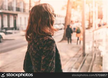 A young woman is walking in the city on a sunny day