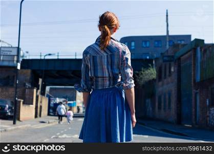 A young woman is walking in the street near a train bridge