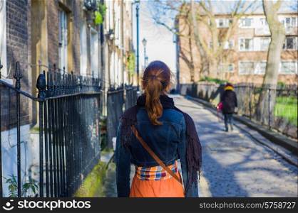 A young woman is walking on a cobbled street of Georgian terraces