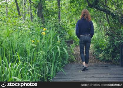 A young woman is walking on a path in a forest