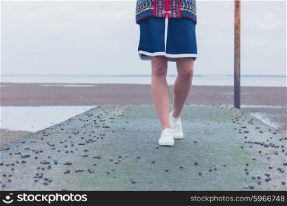 A young woman is walking on a pier by the sea covered in whelks