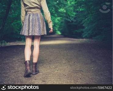 A young woman is walking on a road in the forest