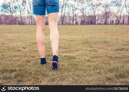 A young woman is walking on the grass in the park