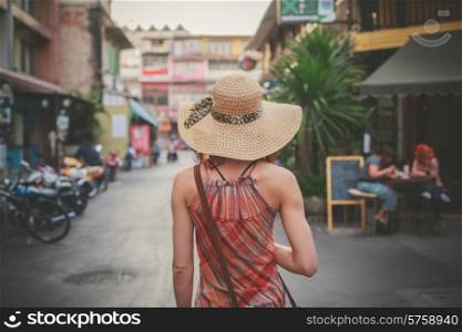 A young woman is walking on the street of an asian country on a sunny day