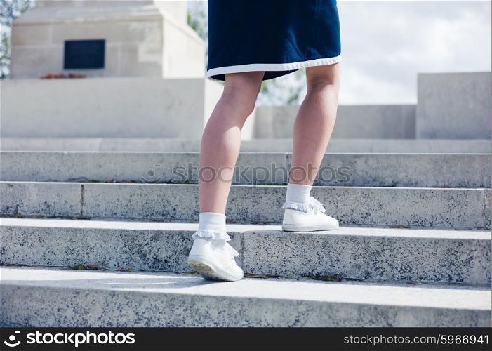 A young woman is walking up the steps of a war memorial