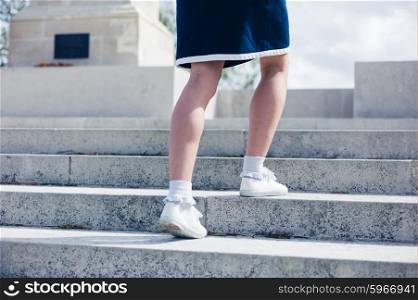 A young woman is walking up the steps of a war memorial
