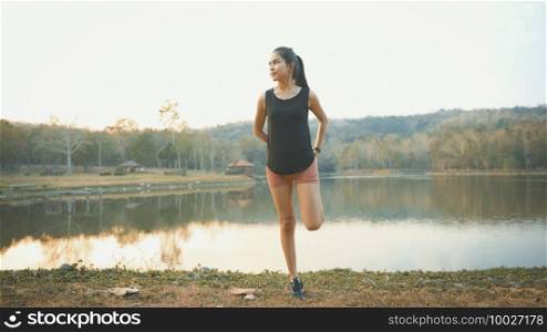 A young woman is warming up before running in nature outdoor at sunset . 