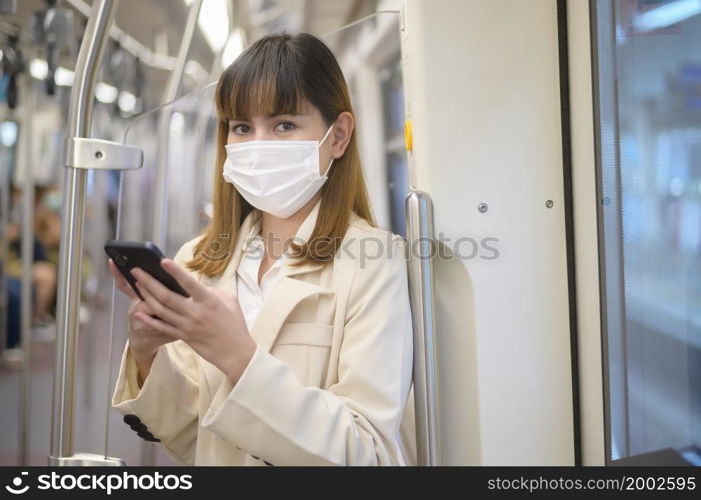 A young woman is wearing protective mask in metro , covid-19 protection , safety travel , new normal , social distancing , safety transportation , travel under pandemic concept. Young woman is wearing protective mask in metro , covid-19 protection , safety travel , new normal , social distancing , safety transportation , travel under pandemic concept