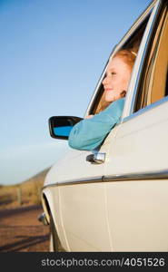 A young woman leaning out of a car window