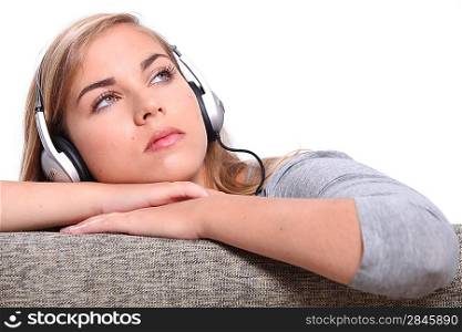 A young woman listening to music on a sofa.