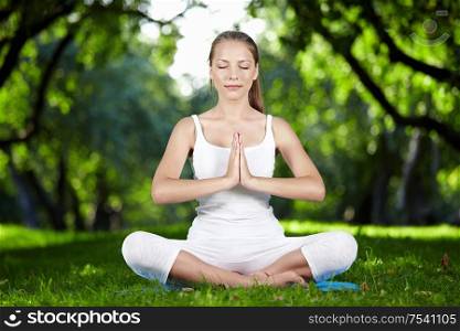 A young woman meditating in park